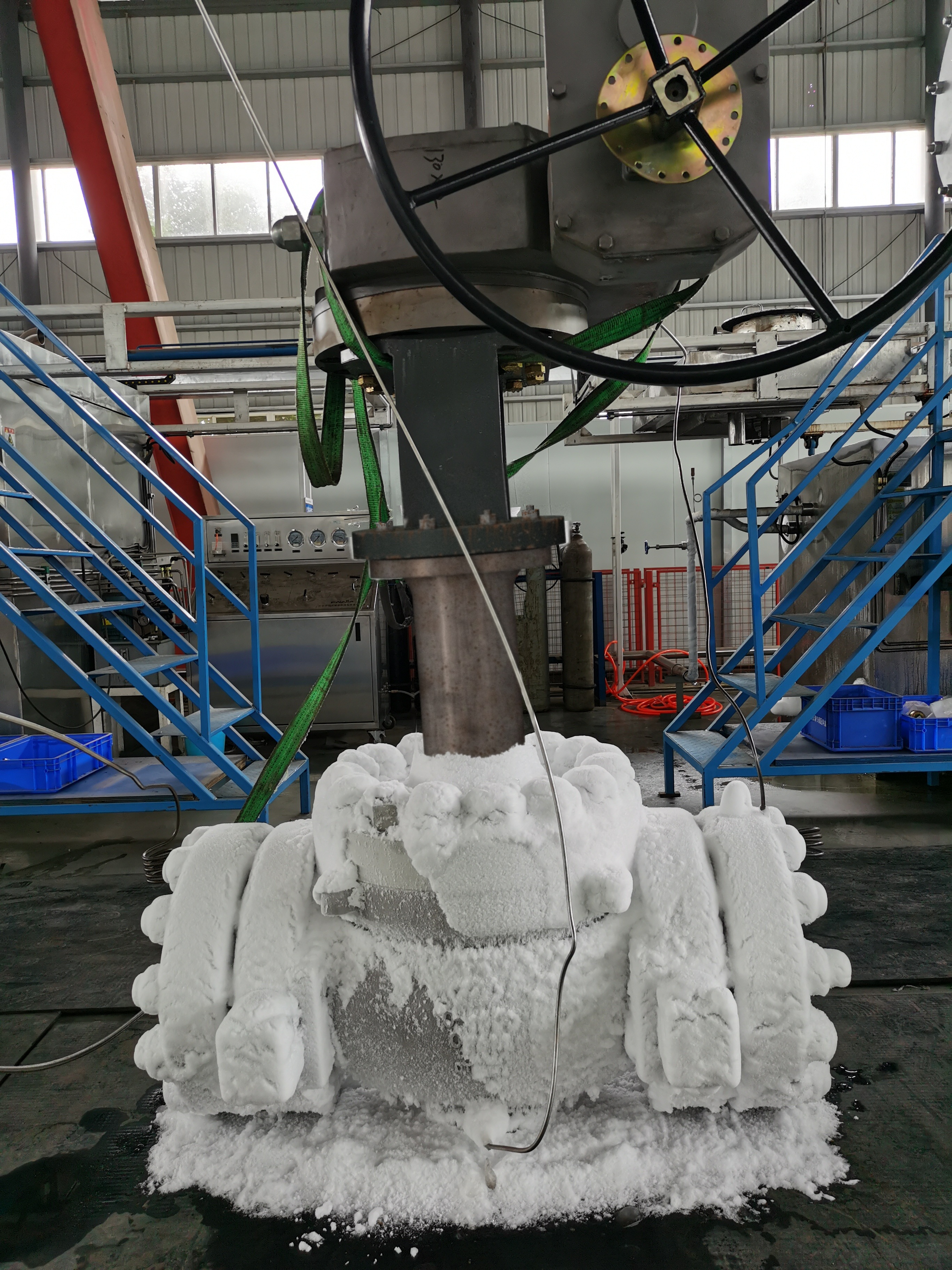 Stainless steel cryogenic ball valve with a long extended bonnet and a pneumatic actuator on top, frost on the lower body and flanges only